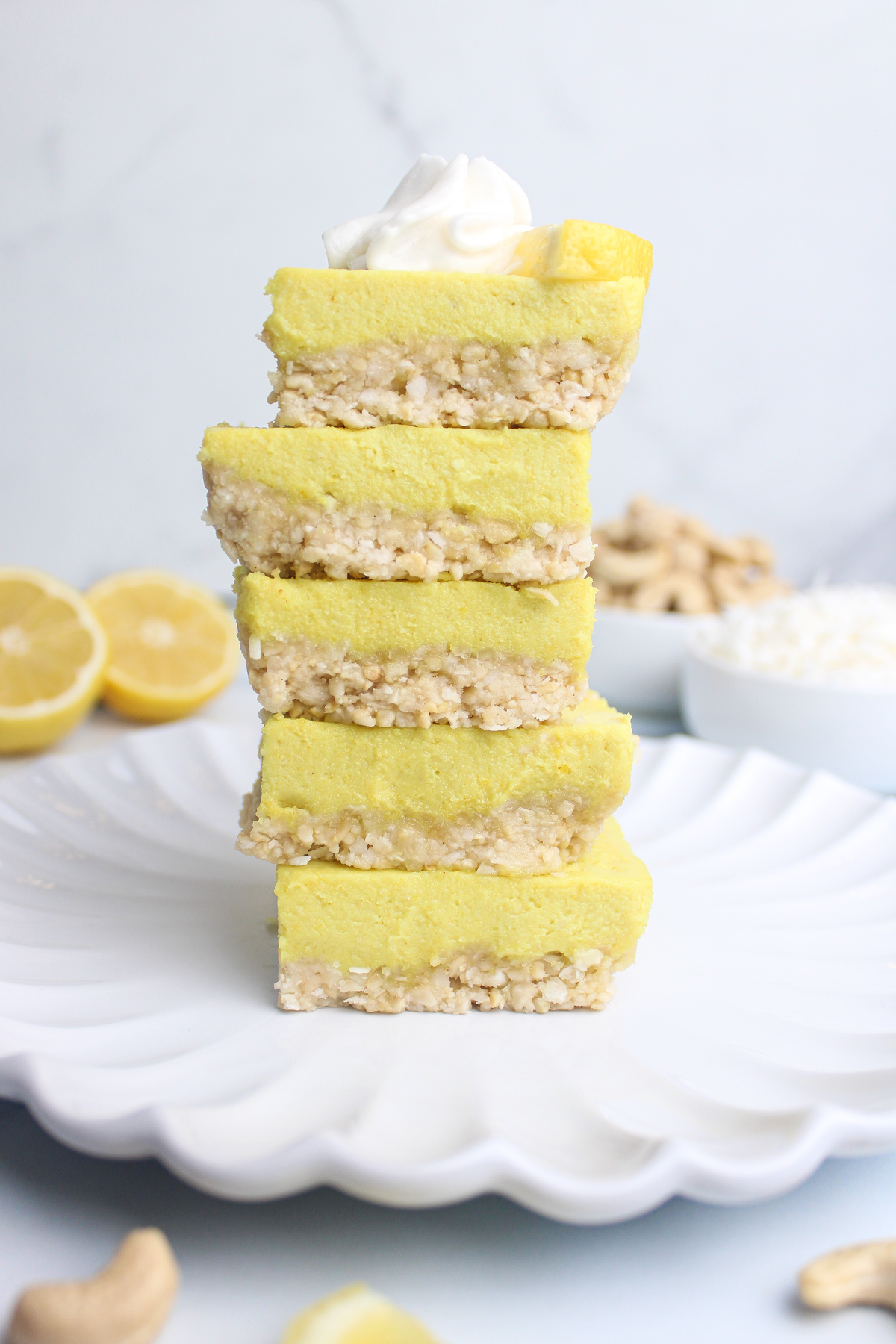 Five tangy no-bake vegan lemon cheesecake squares stacked on a plate.