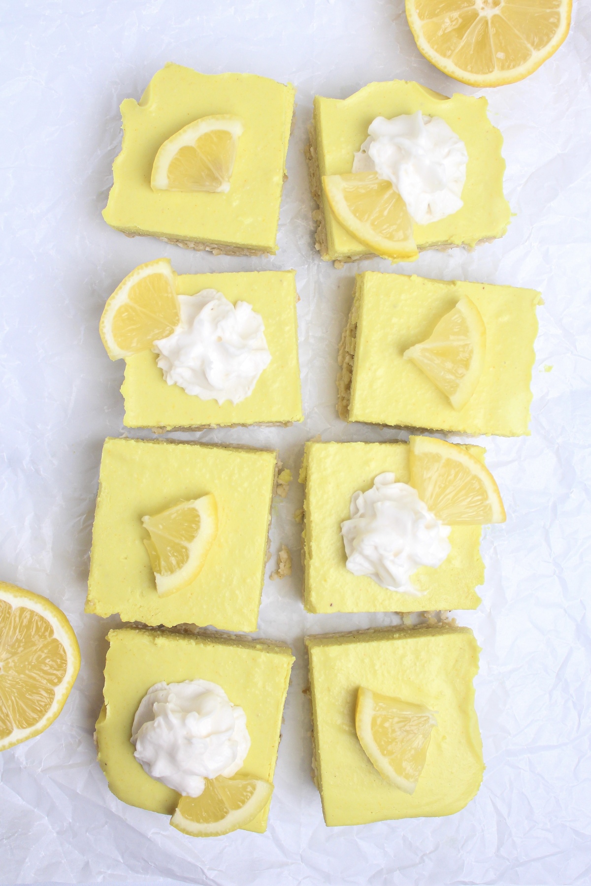 Overhead shot of lemon cheesecake bars arranged on a piece of parchment paper.