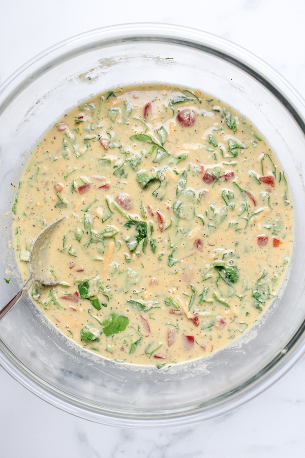 Diced tomatoes, red bell pepper, spinach, and shredded non-dairy cheddar mixed into chickpea flour muffin batter.