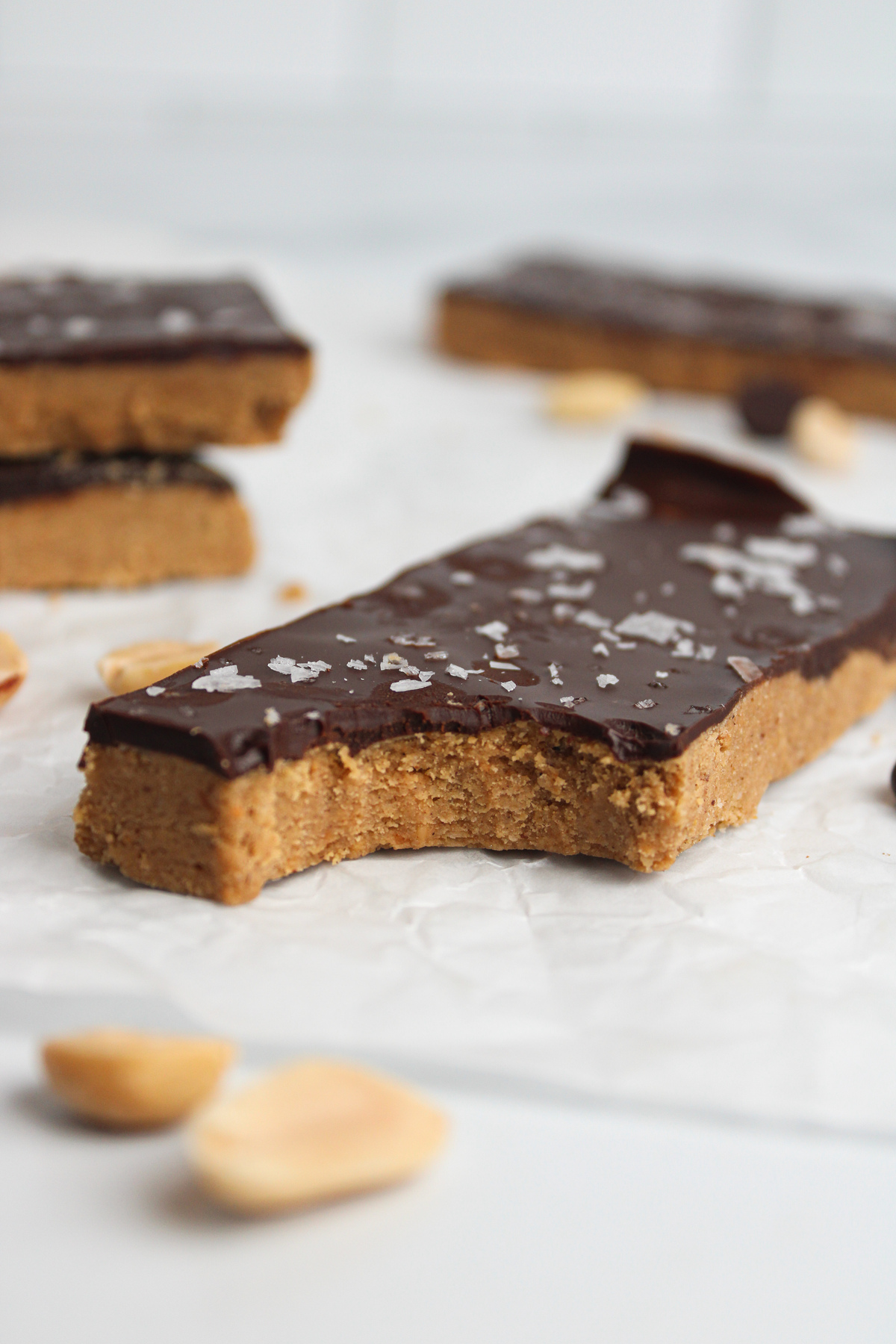 Close-up of a homemade protein bar with a bite taken out of it, showing the soft peanut butter base and chocolate topping.