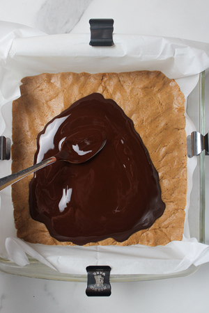 Spreading melted chocolate over the peanut butter layer.