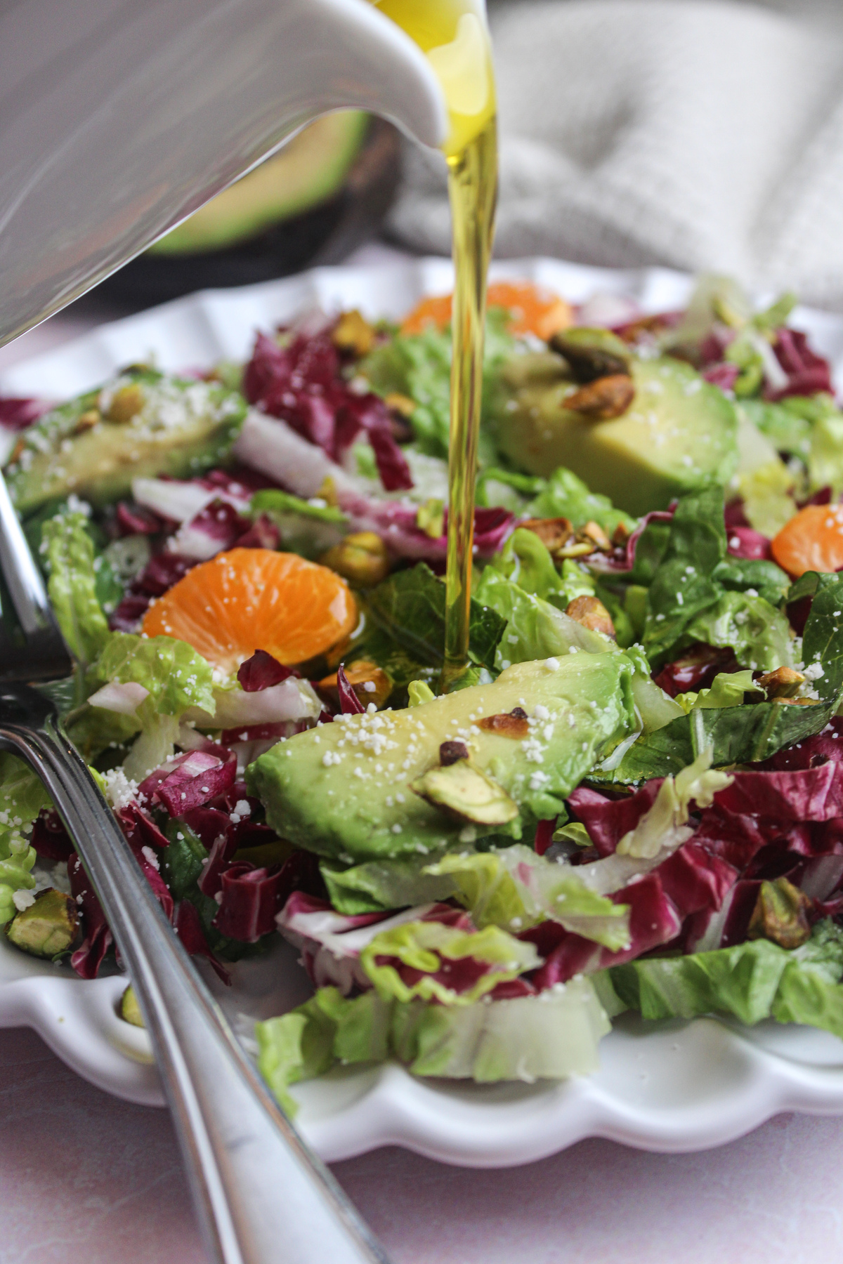 Pouring vinaigrette dressing over a fresh radicchio salad.