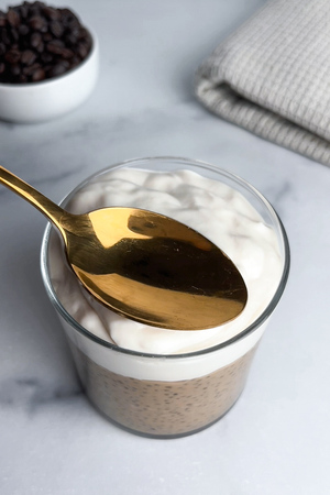 Spreading yogurt on top of thickened chia pudding.