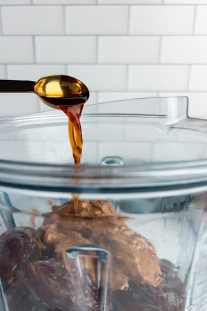 Dates, coconut oil, almond butter, vanilla, and salt in a blender, ready to be blended into caramel.