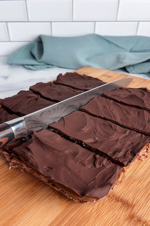 Cutting the finished caramel slice with a knife.