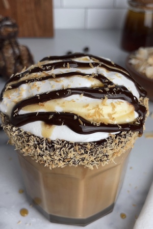 Finished latte drizzled with chocolate and caramel syrup, sprinkled with toasted coconut.
