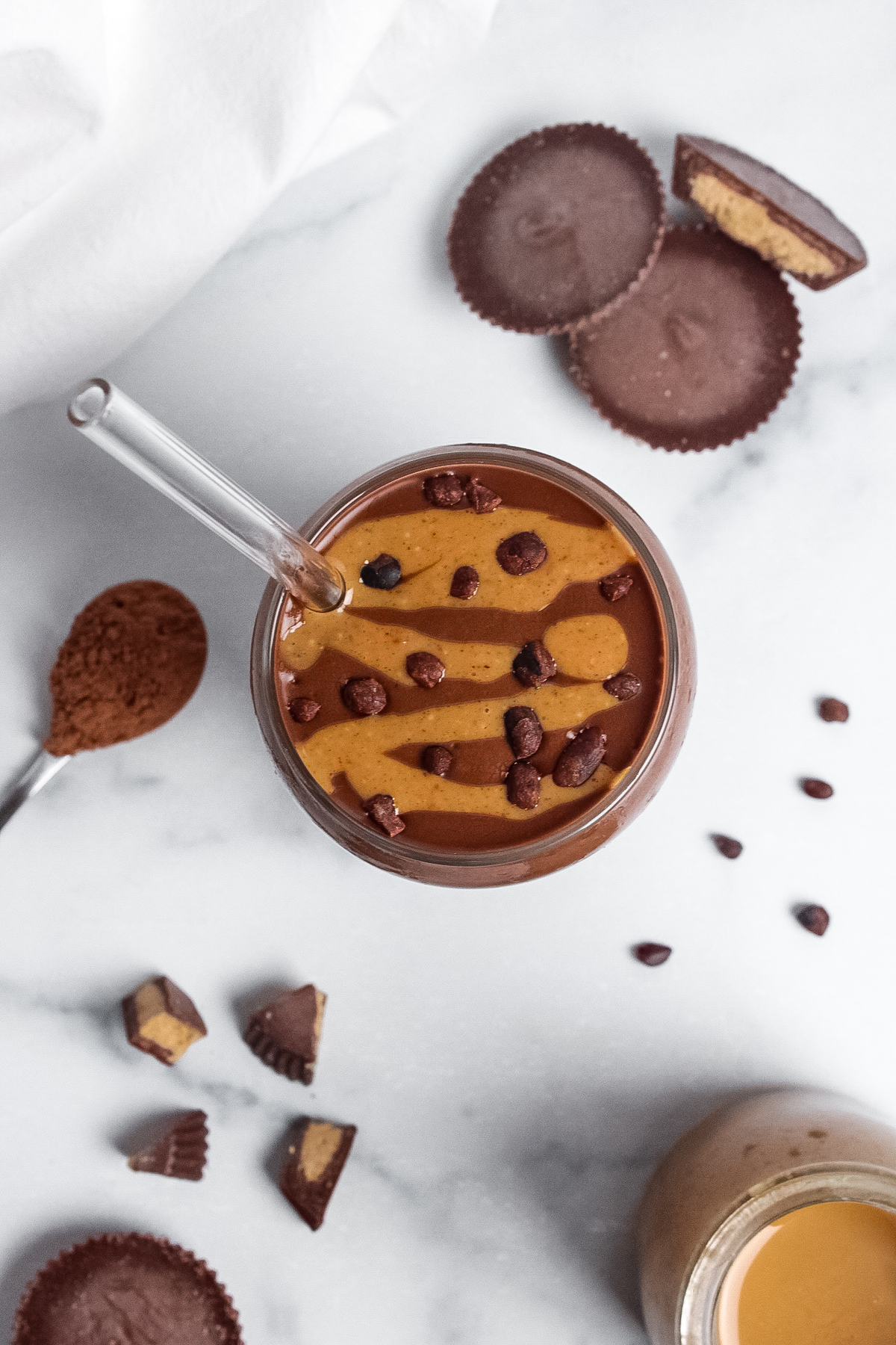 Overhead of a peanut butter cup protein smoothie, showing the peanut butter drizzle and cacao nibs on top.