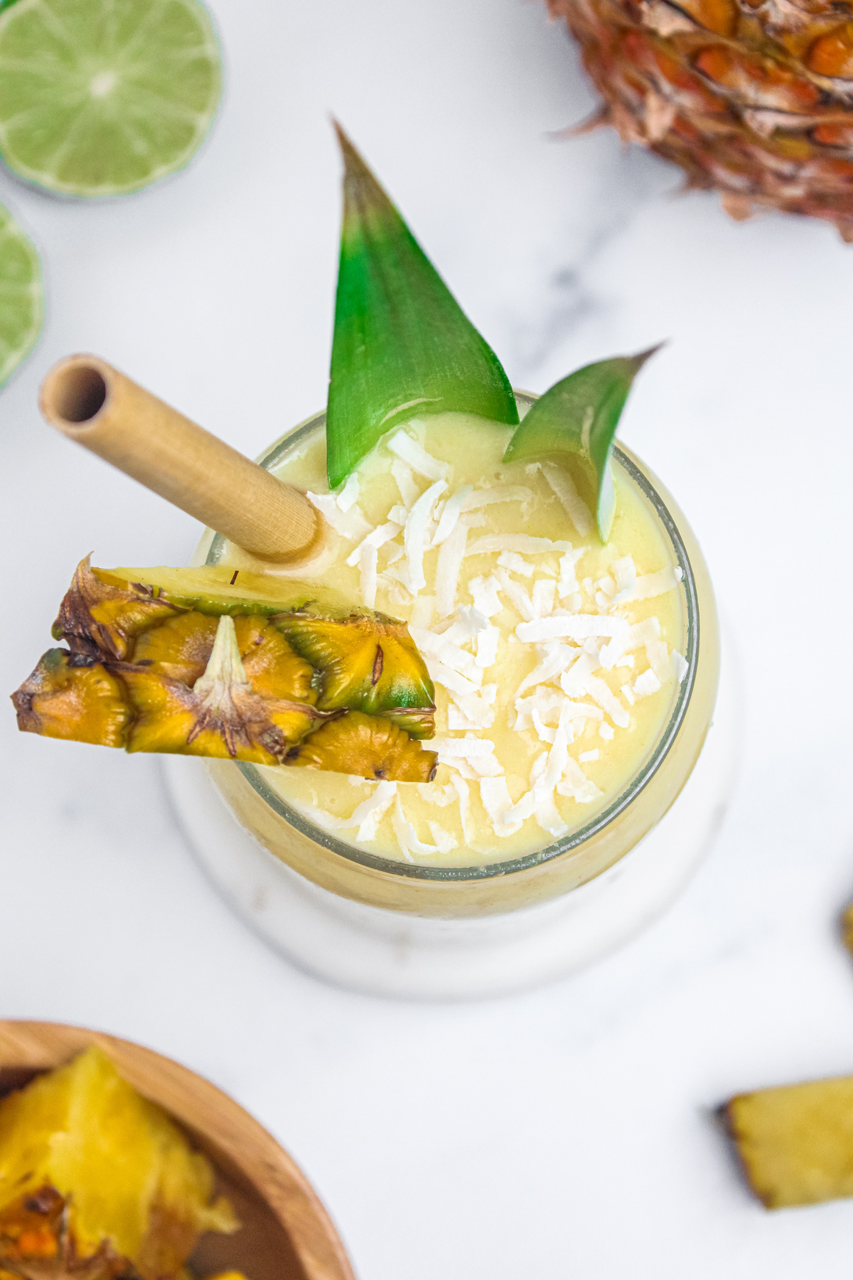 Overhead view of a creamy piña colada mocktail, topped with a pineapple wedge and shredded coconut.
