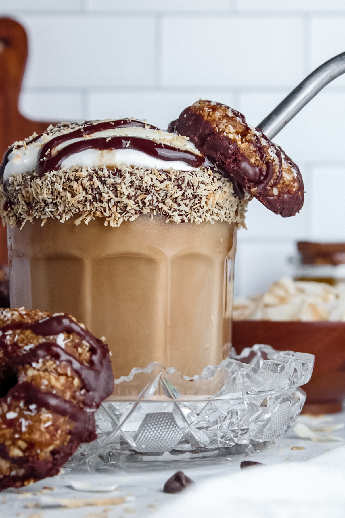 Straight-on view of a latte in a glass with a Samoa cookie on the straw.