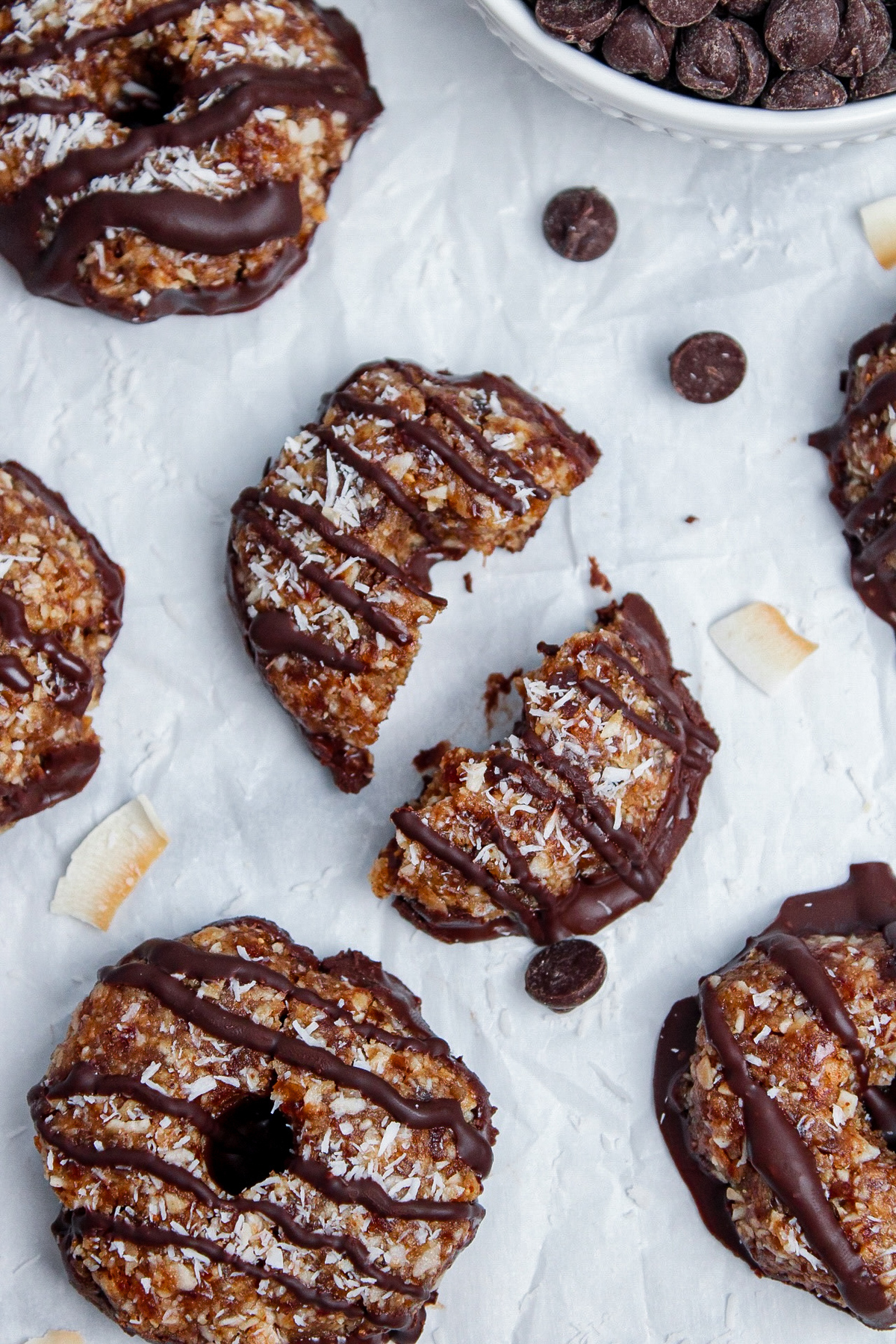 Overhead close-up of no-bake Samoa cookies on parchment paper, with one cookie broken in half.