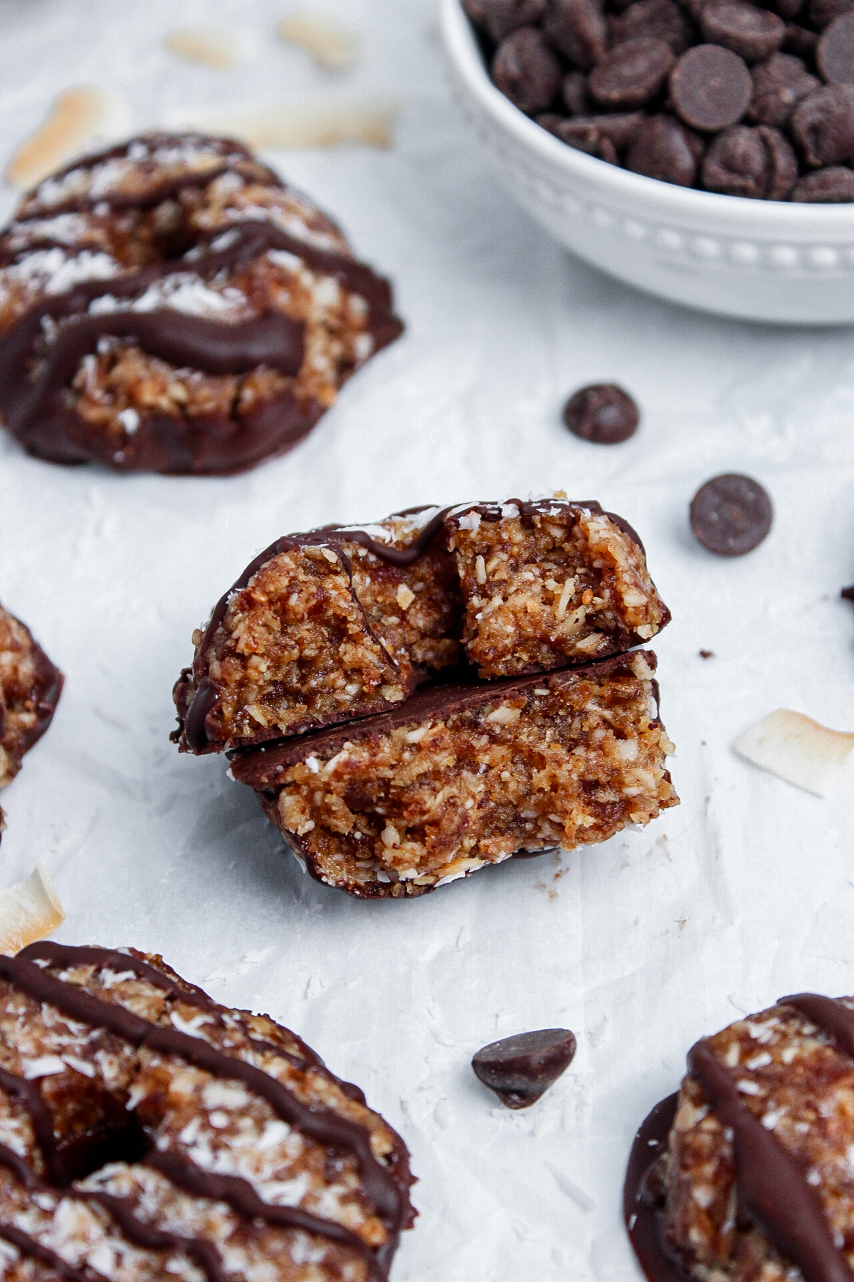 Close-up of a no-bake Samoa cookie made with dates and coconut, broken in half to show its crumbly texture.