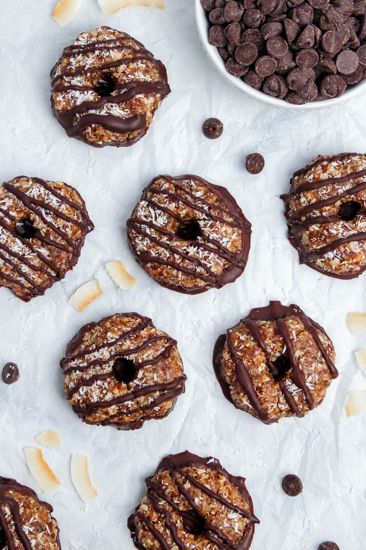 Overhead view of healthy no-bake Samoa cookies drizzled with chocolate, arranged on parchment paper.