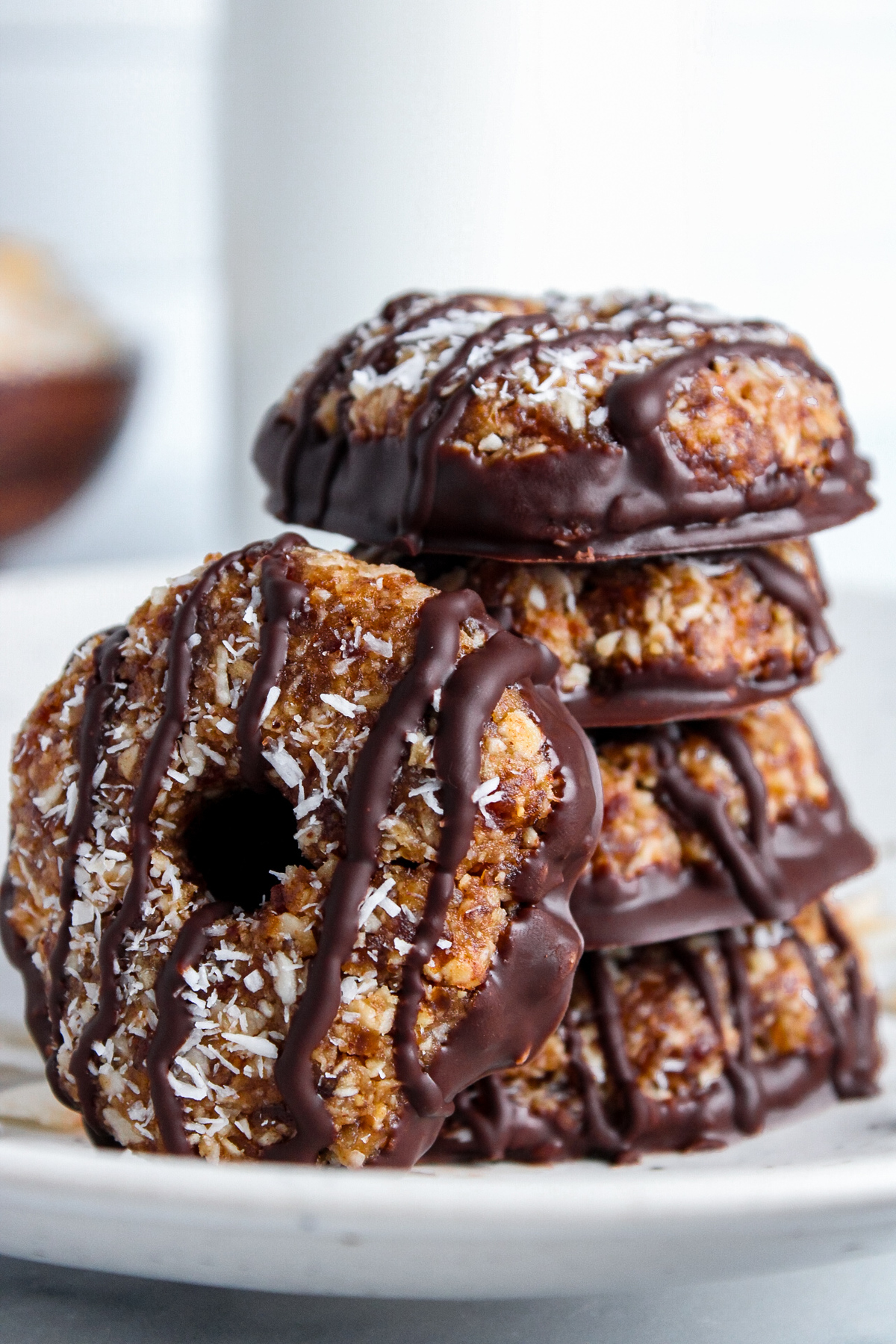 Close-up of a stack of healthy no-bake Samoa cookies, with one cookie on its side leaning against the stack.