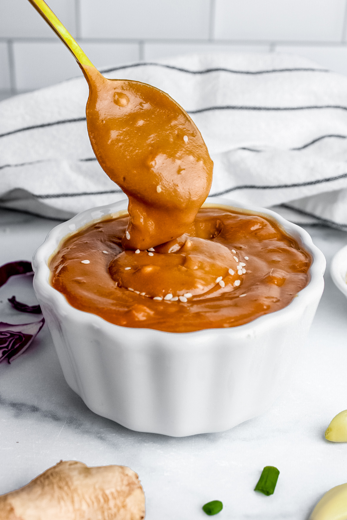 Thick, creamy peanut dressing for spring roll salad shown being scooped with a spoon.