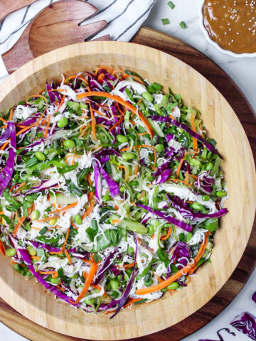 Fresh spring roll salad with red cabbage, carrots, cucumber, and edamame in a large wooden bowl.