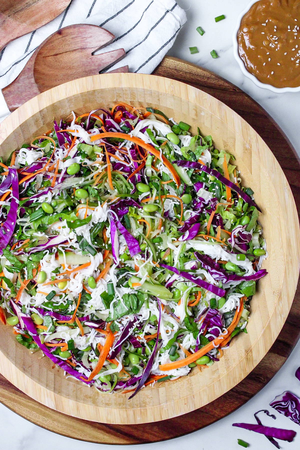 Fresh spring roll salad with red cabbage, carrots, cucumber, and edamame in a large wooden bowl.