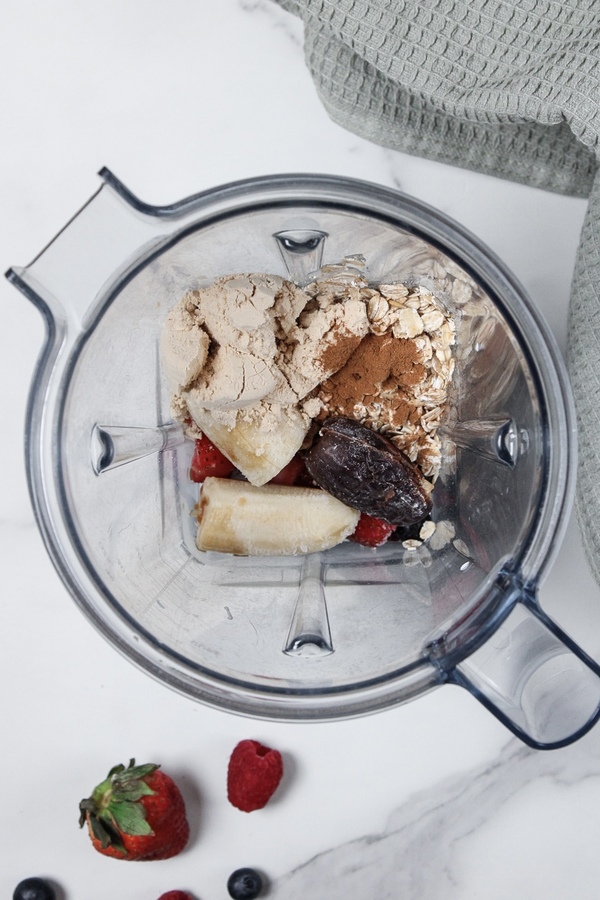 Berry pie smoothie ingredients added to a blender.