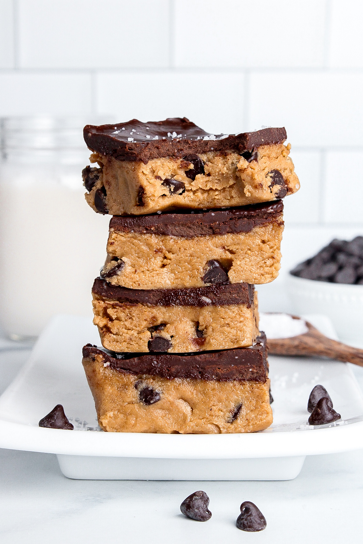 Stack of four healthy cookie dough bars with chocolate chips and ganache topping.