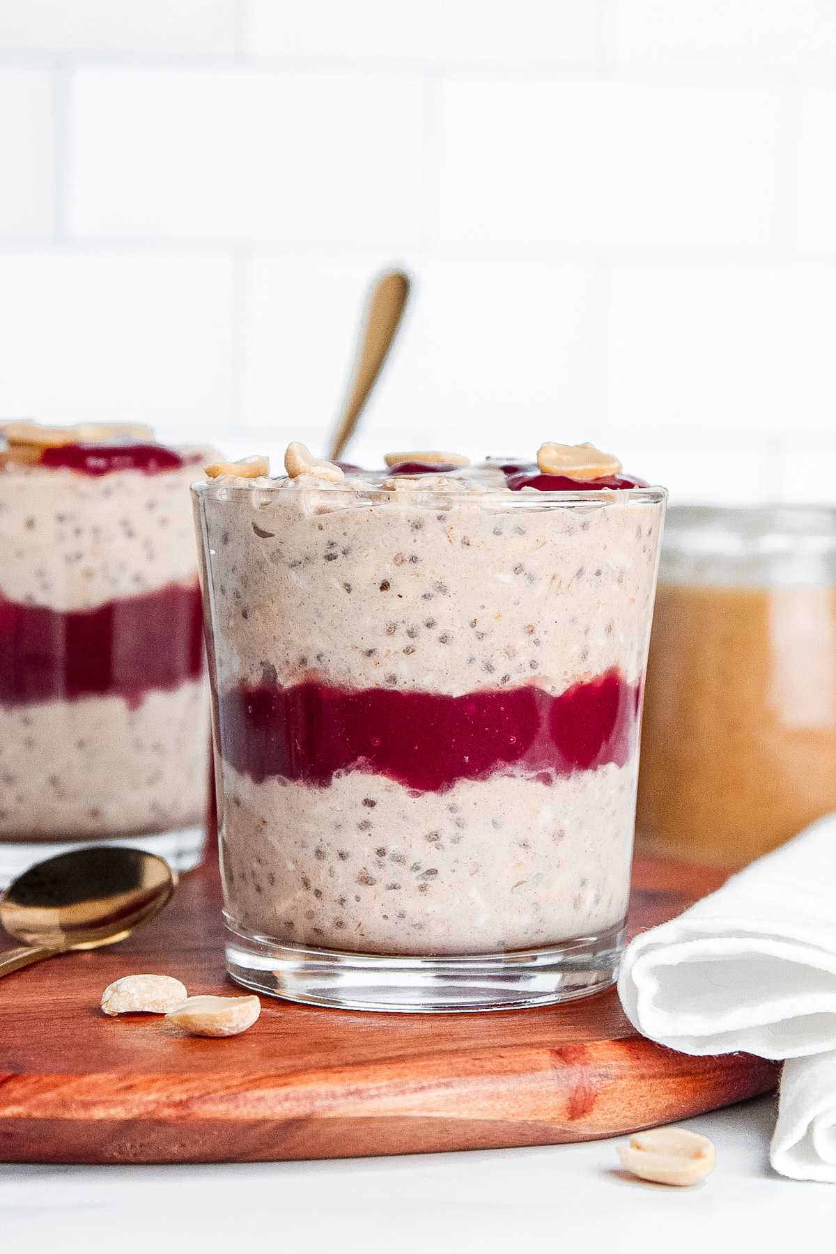 Straight-on shot of two glasses of PB&J overnight oats, showing layers of creamy oats and raspberry jam.