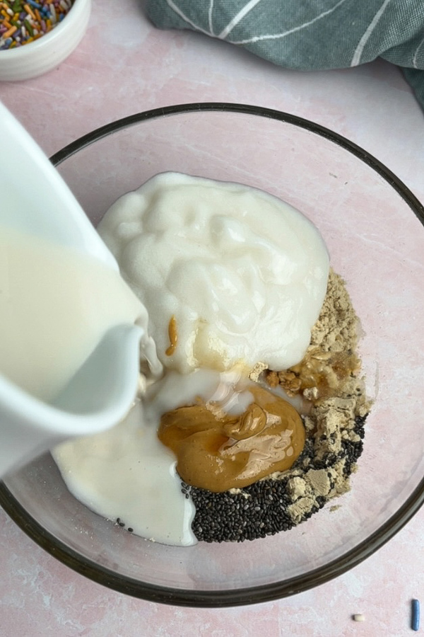 All ingredients for birthday cake overnight oats added to a bowl.