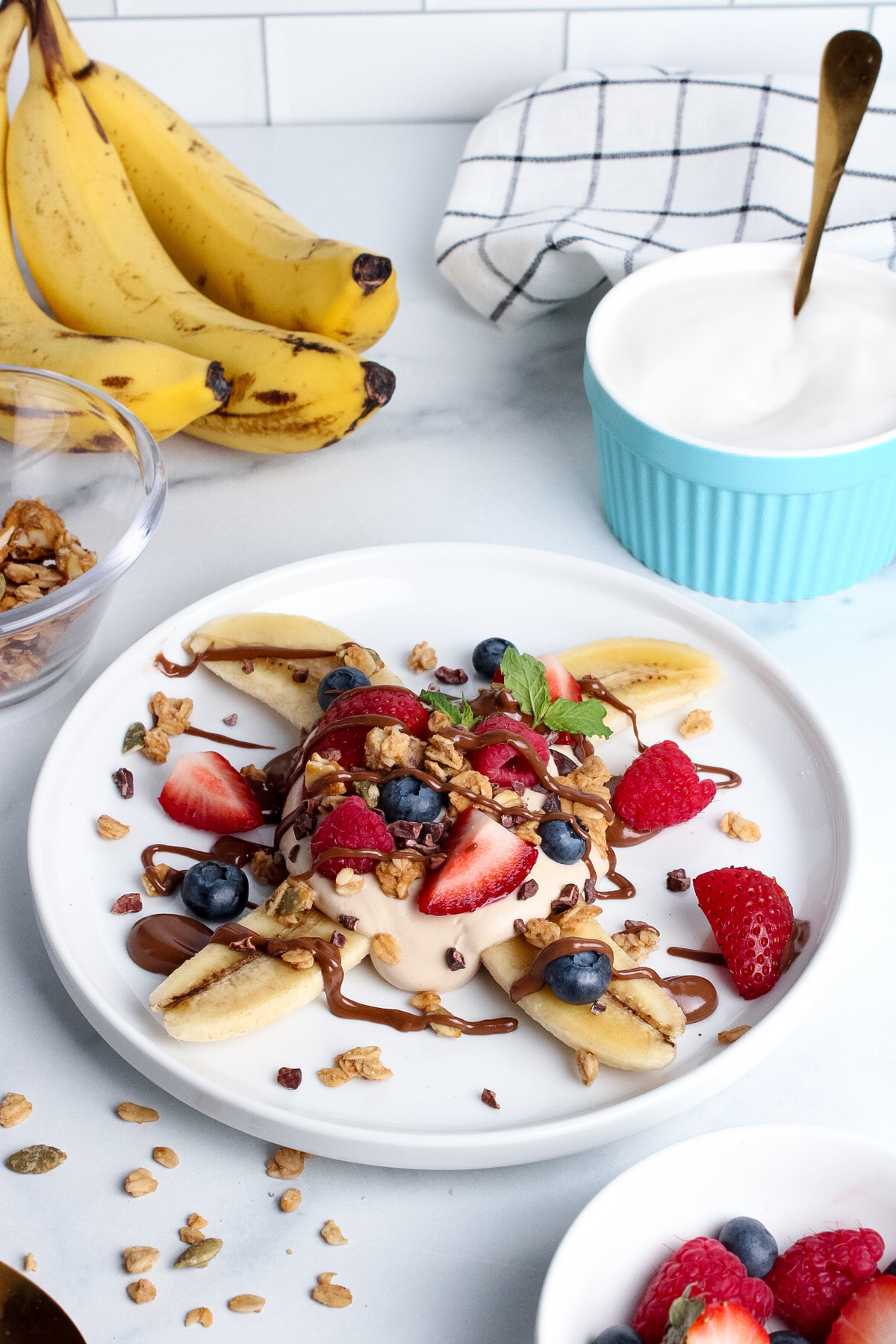 Low-angle view of a breakfast banana split with yogurt, fruit, and granola.