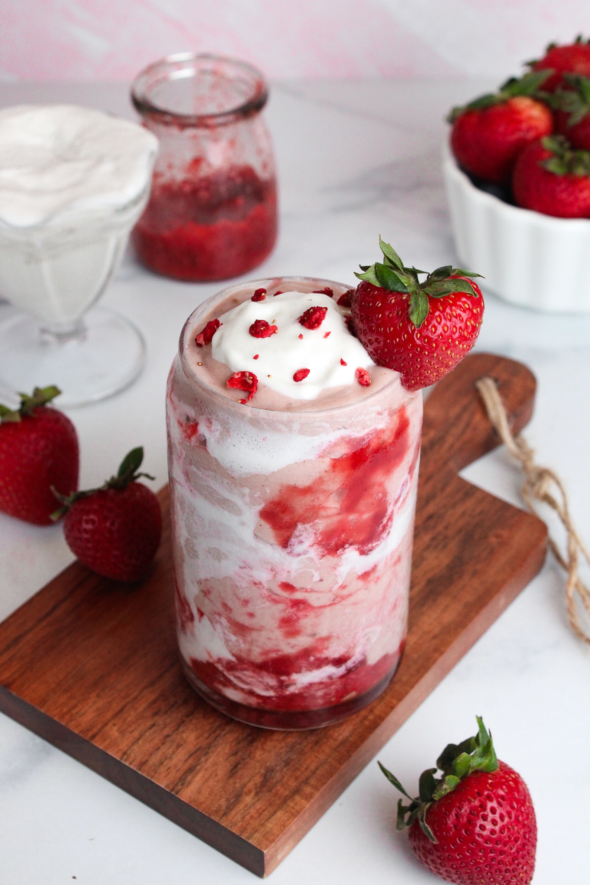 Angled view of a creamy strawberry glaze smoothie with coconut cream and strawberry glaze swirled around the inside of the glass.