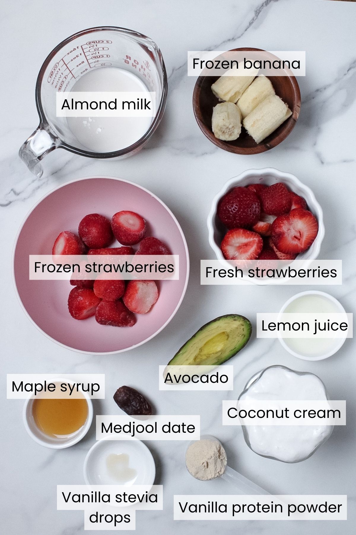 Ingredients for a strawberry glaze smoothie: frozen strawberries, maple syrup, lemon juice, frozen banana, avocado, Medjool date, vanilla protein powder, vanilla stevia drops, almond milk, and coconut cream.