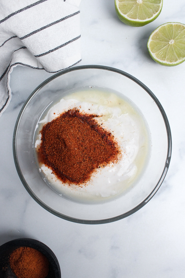 Non-dairy yogurt, lime juice, and taco seasoning combined in a bowl.