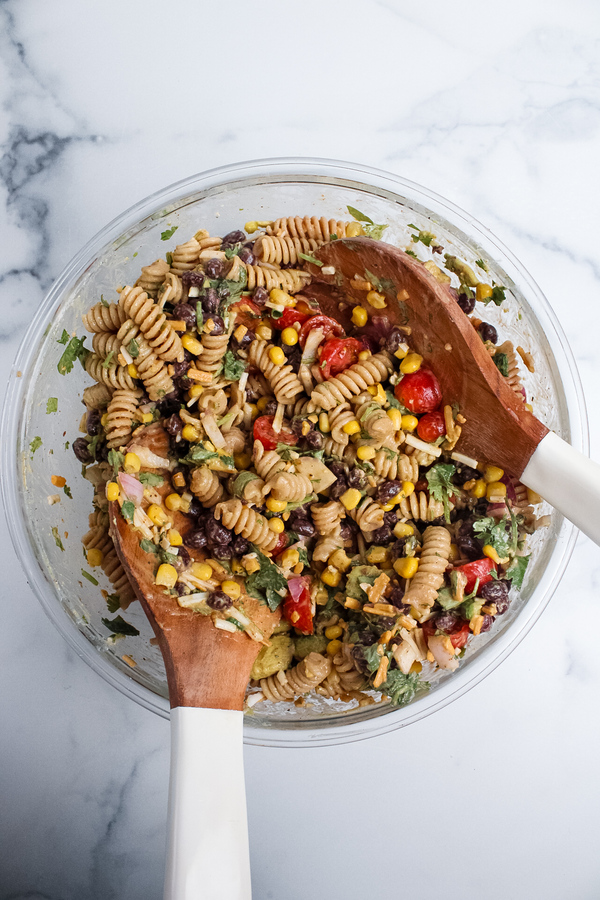 Vegan taco pasta salad tossed with salad servers until well combined and evenly coated in dressing.