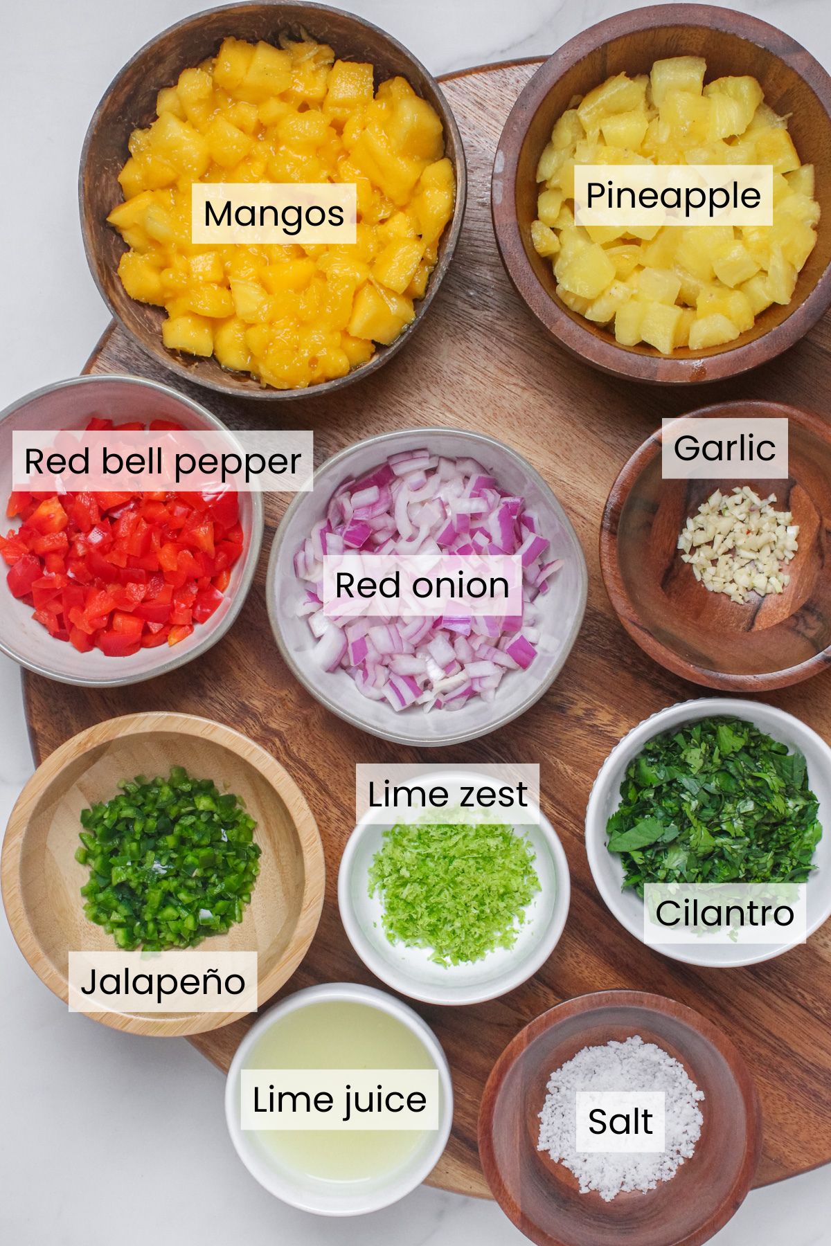 Ingredients needed for mango pineapple salsa: mangos, pineapple, red bell pepper, red onion, garlic, jalapeño, lime zest and juice, cilantro, and salt.