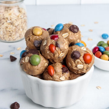 Bowl of colorful vegan monster cookie energy balls made with oats, peanut butter, and chocolate candies.