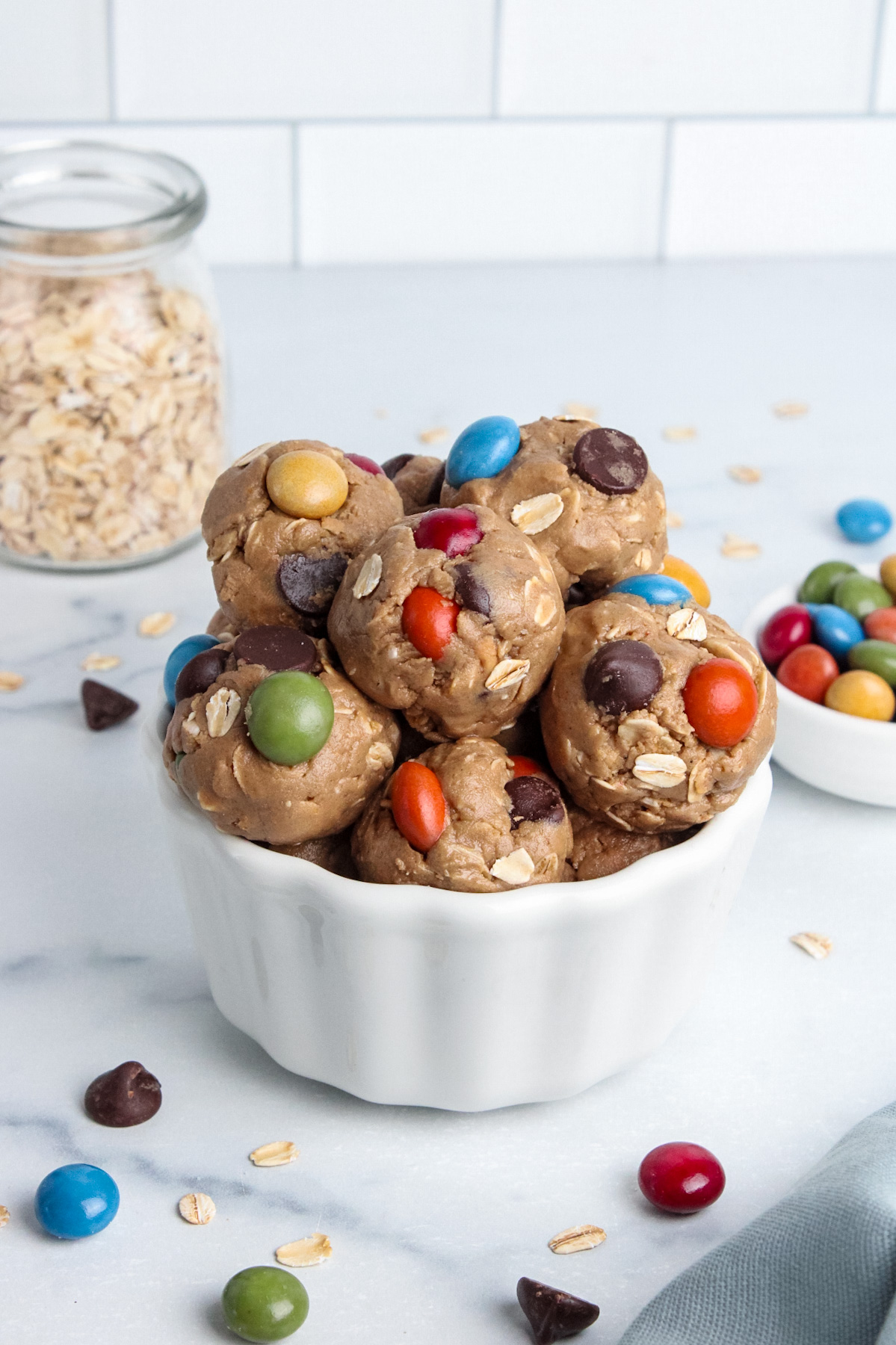 Bowl of colorful vegan monster cookie energy balls made with oats, peanut butter, and chocolate candies.