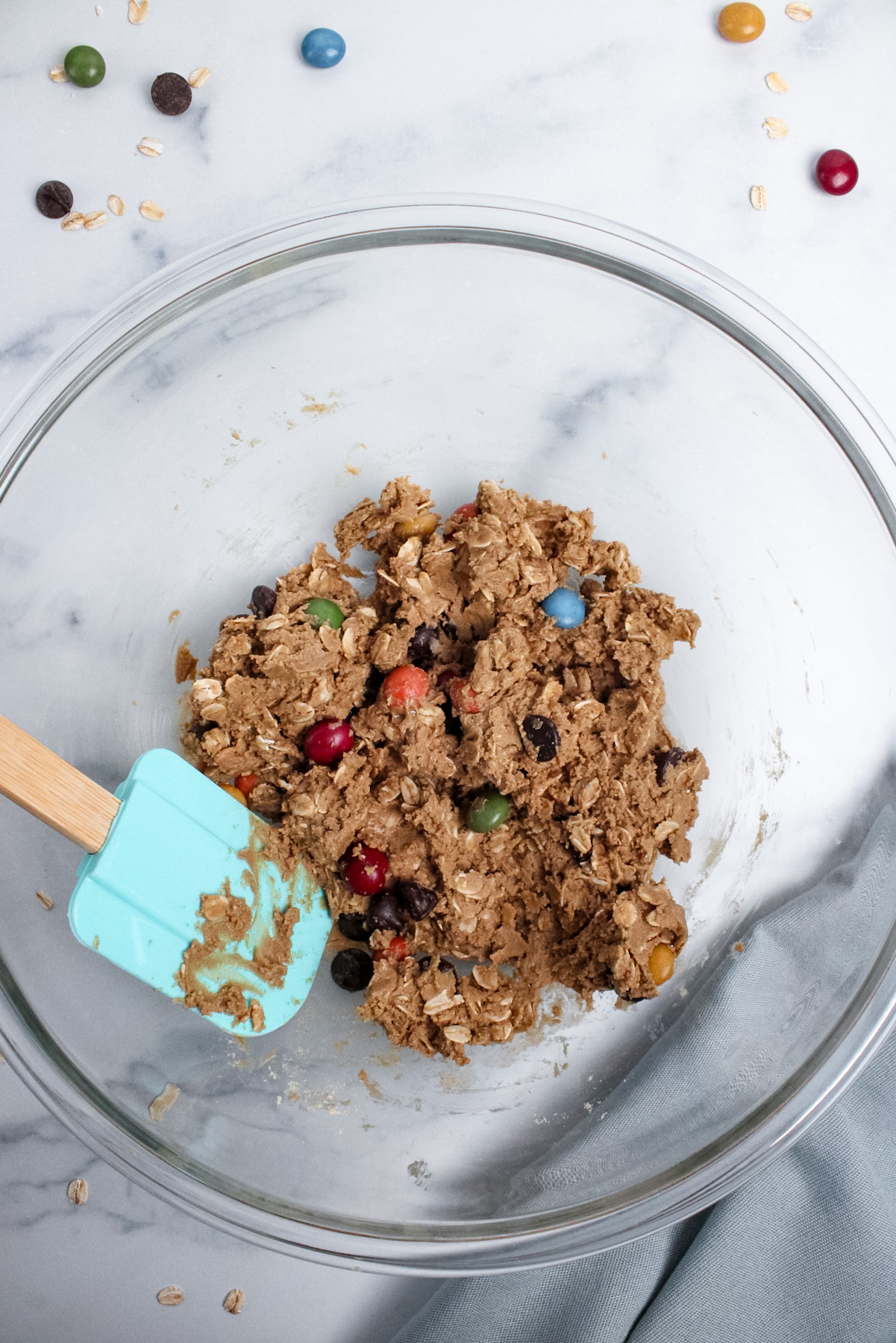 Fully mixed monster cookie energy ball dough in a glass bowl with a spatula.
