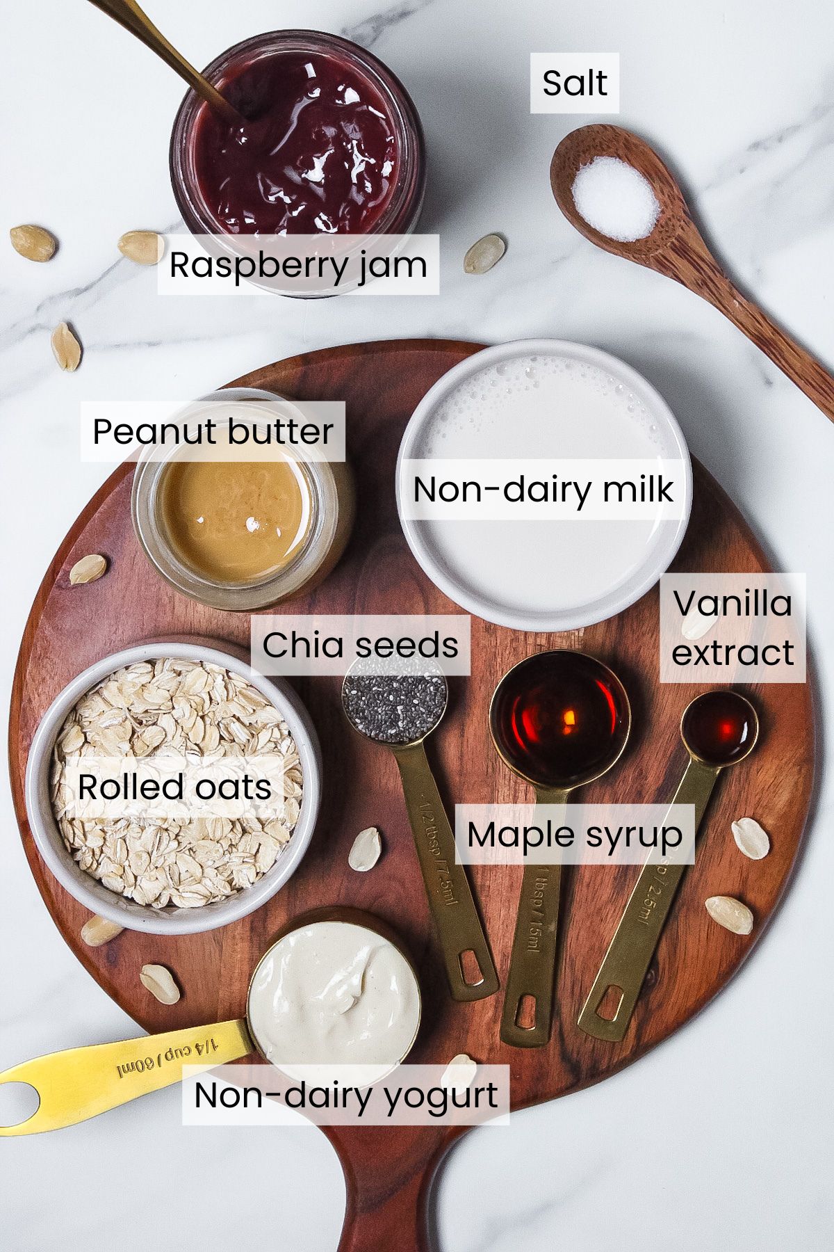 Ingredients for PB and J overnight oats: rolled oats, non-dairy milk, non-dairy yogurt, peanut butter, maple syrup, chia seeds, vanilla extract, salt, and raspberry jam.