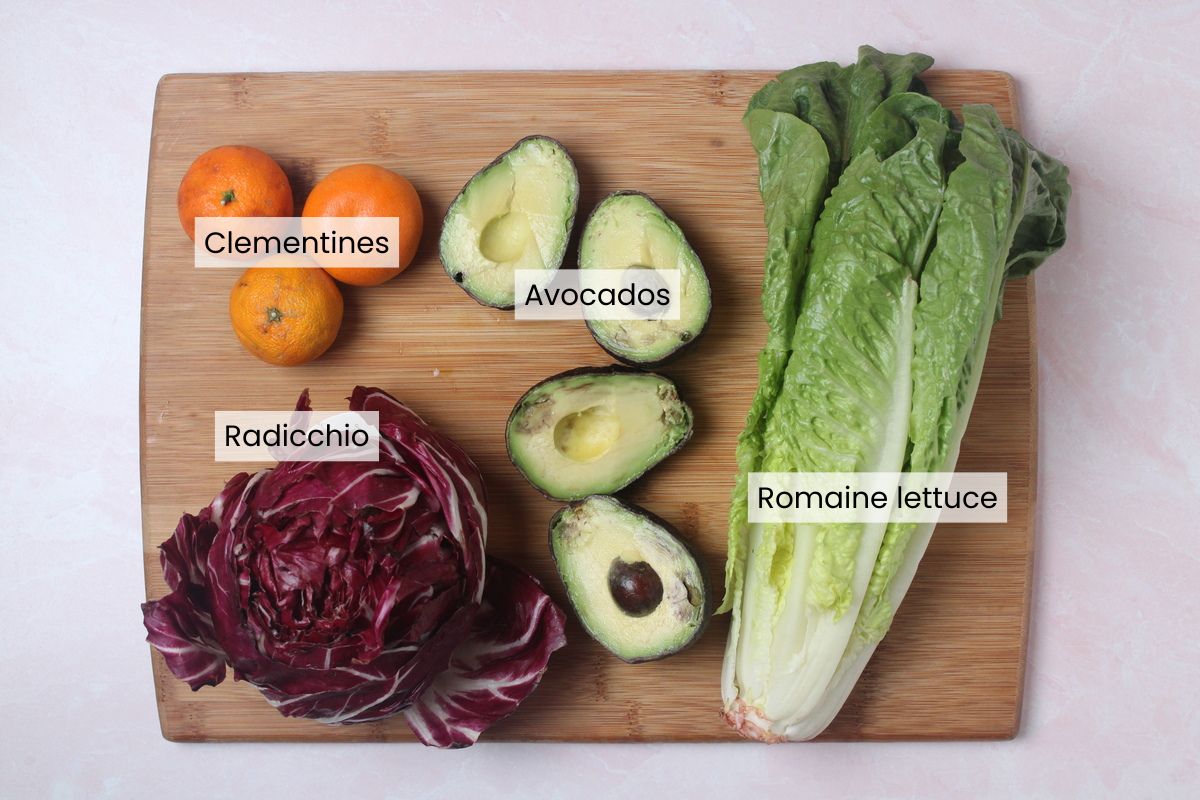 Ingredients for the base of a radicchio, orange, and pistachio salad: clementines, avocados, radicchio, and romaine lettuce.