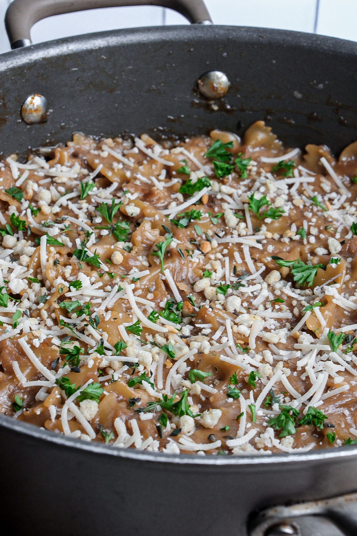 Pot of French onion pasta made with farfalle and finished with dairy-free parmesan.