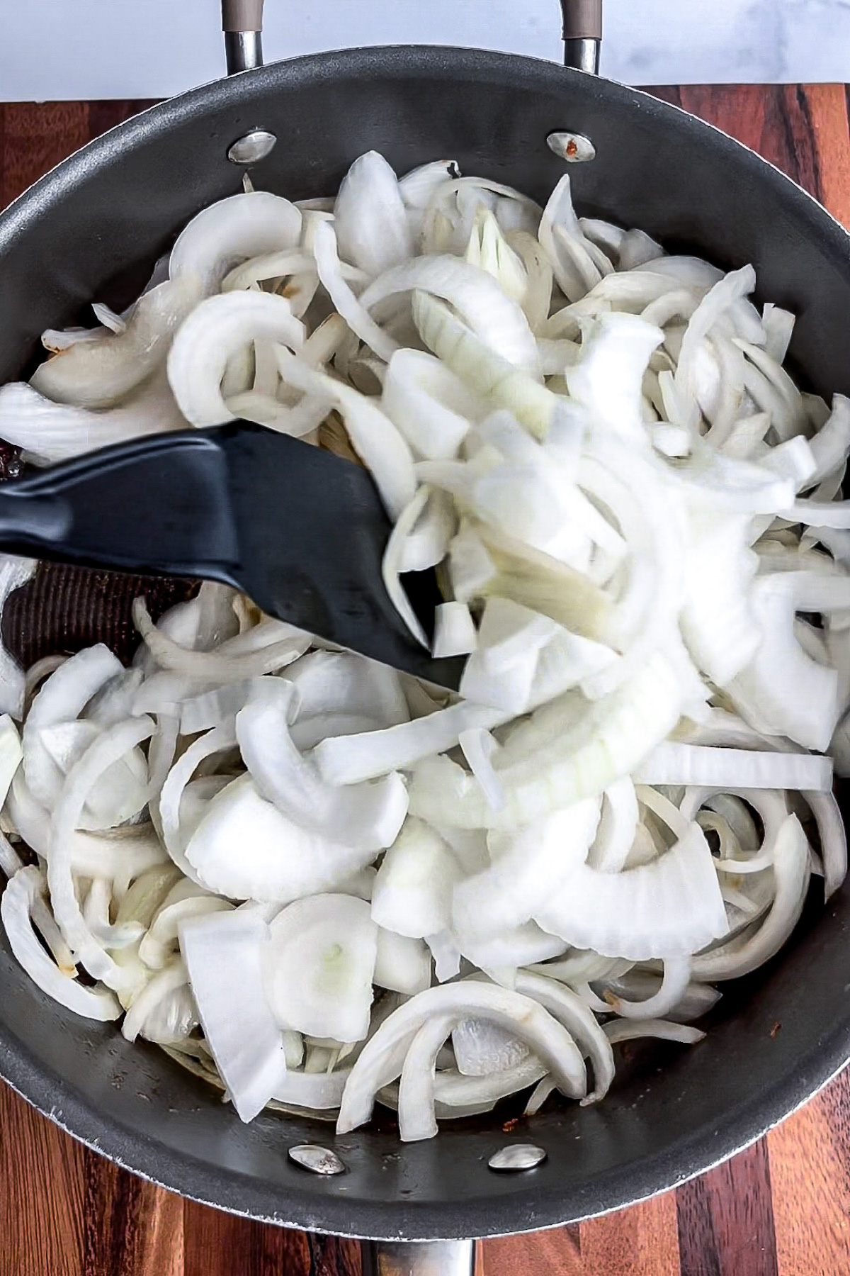 Sliced onions cooking in a pot with vegan butter.