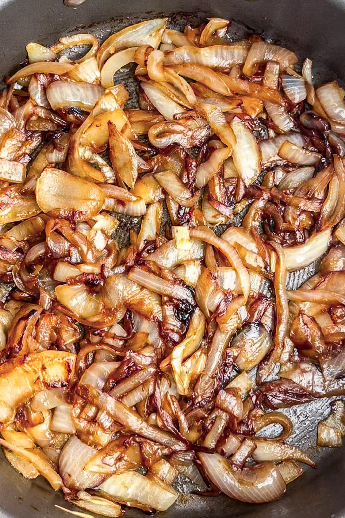 Deeply caramelized onions, golden brown and jammy, in a pot.