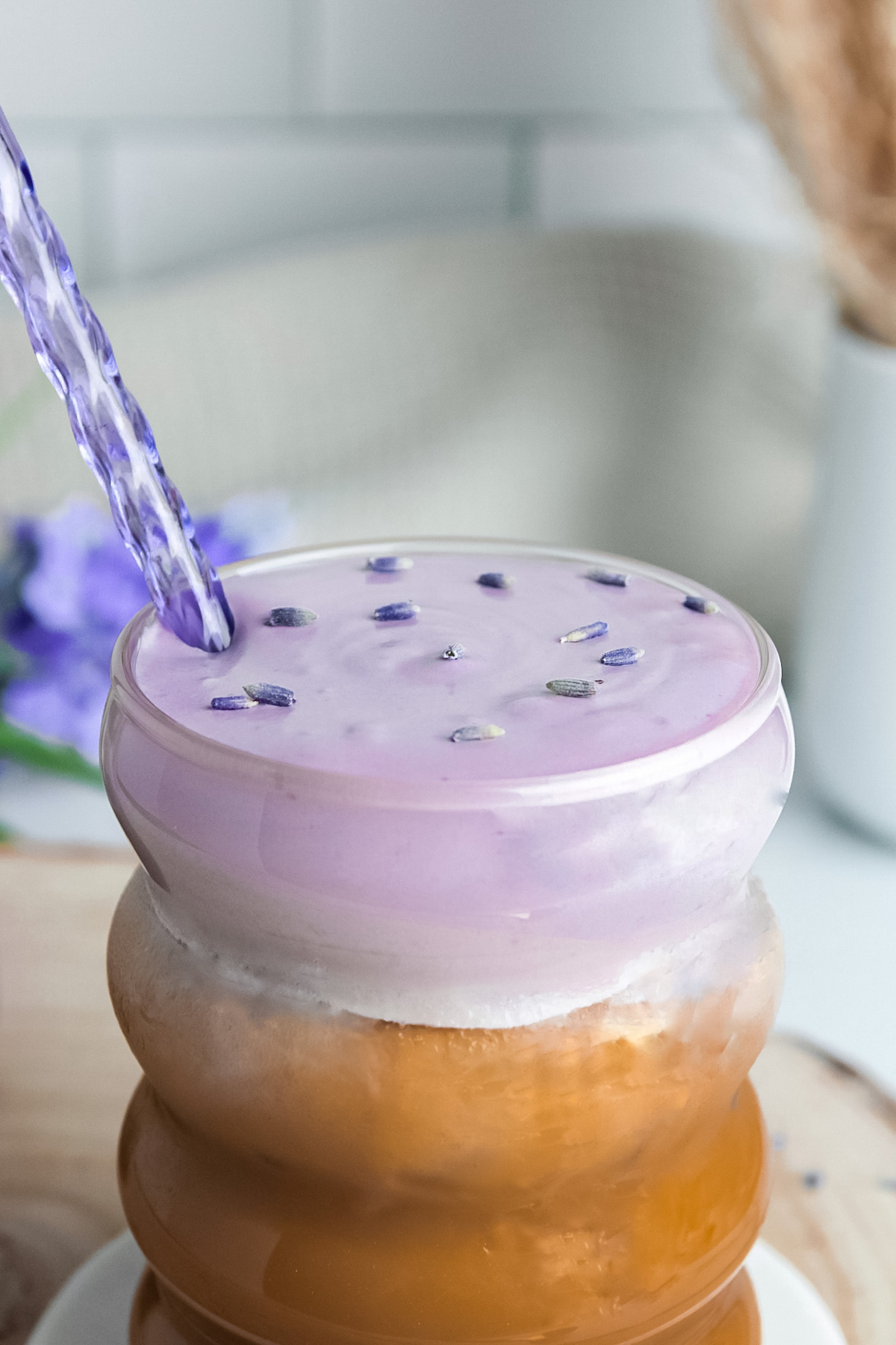 Close-up of an iced oat milk latte topped with lavender cold foam.