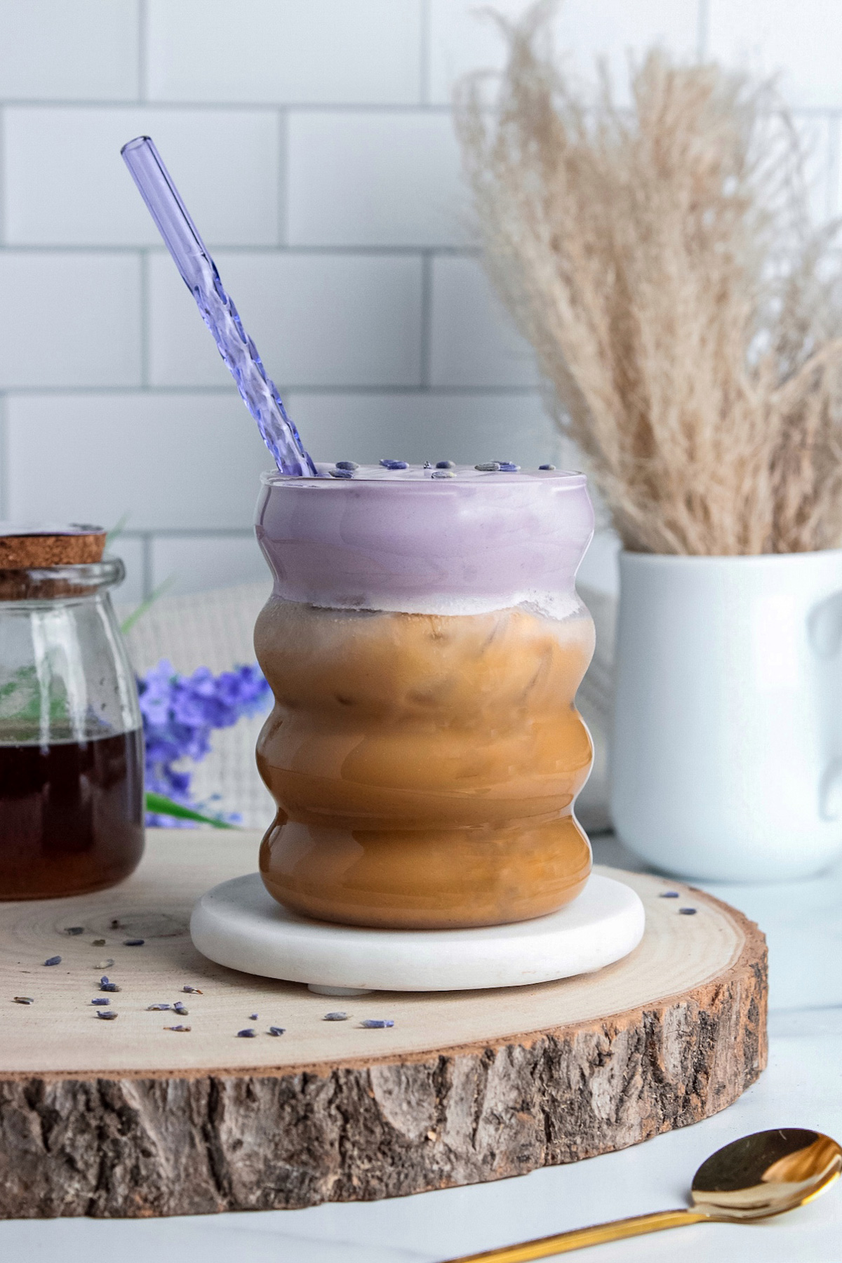 Iced lavender cream latte in a glass, made with oat milk and espresso, topped with purple lavender cold foam.