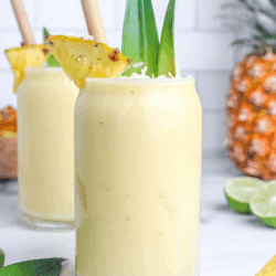 Creamy piña colada mocktail in a glass, garnished with fresh pineapple and coconut, with a bamboo straw.