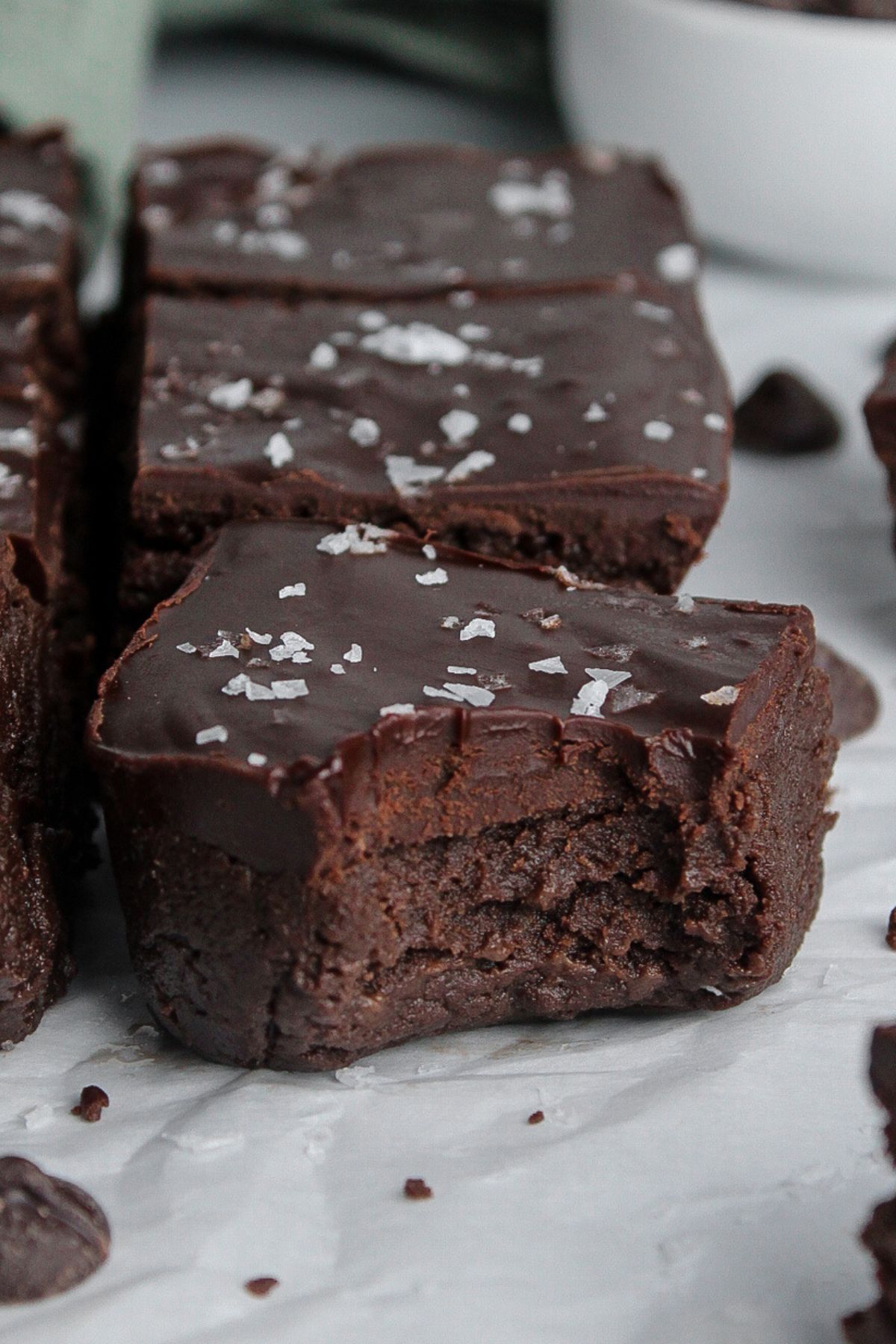 Close-up of a fudgy no-bake protein brownie with a bite taken out, highlighting the glossy chocolate ganache.