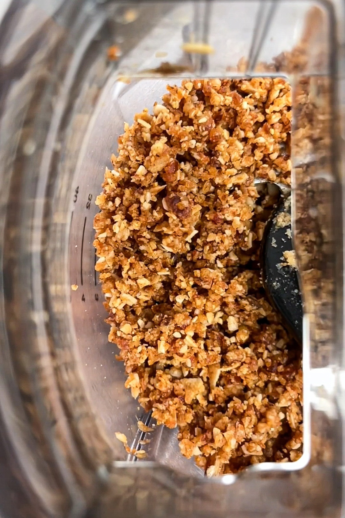 Toasted coconut, dates, almond butter, vanilla extract, and salt pulsed together in a food processor until a sticky, orange-brown mixture forms.