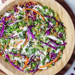 Fresh spring roll salad with red cabbage, carrots, cucumber, and edamame in a large wooden bowl.