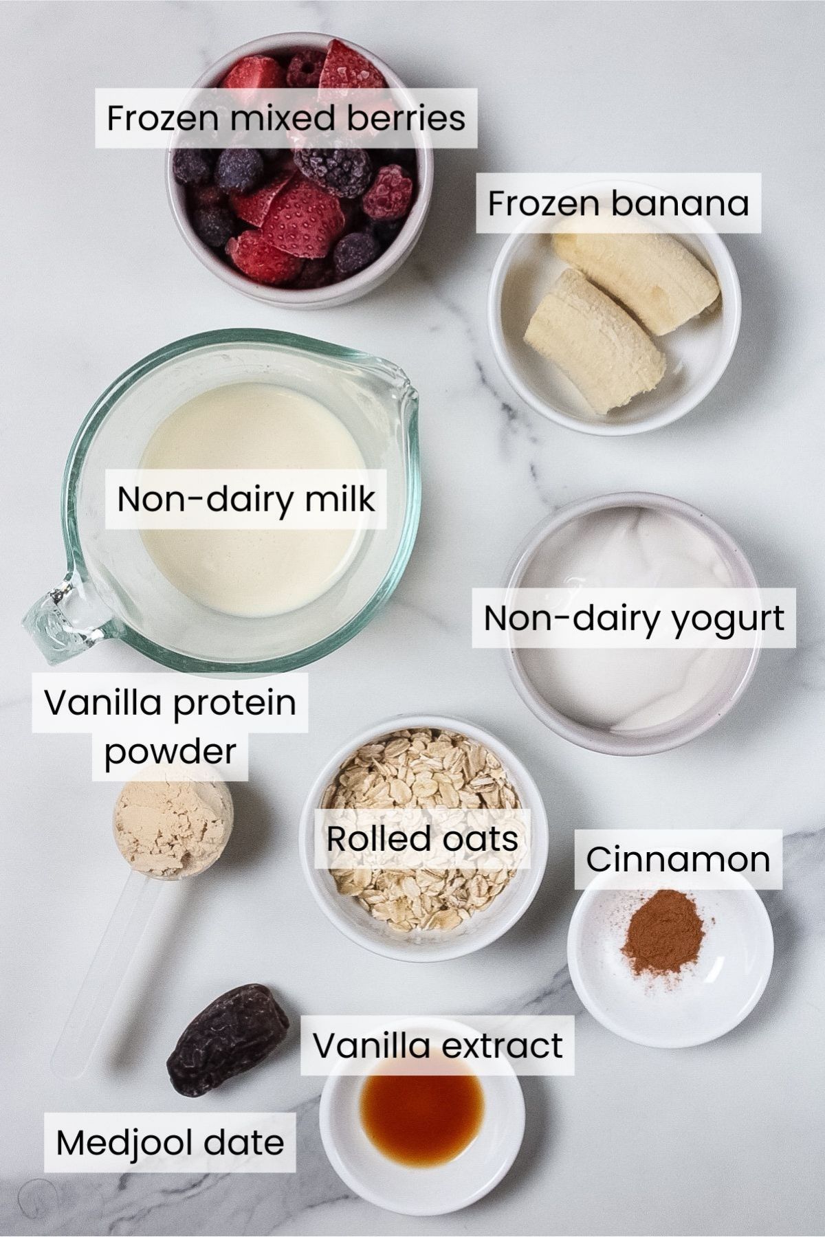 Ingredients for a berry pie smoothie: frozen mixed berries, frozen banana, non-dairy yogurt, vanilla protein powder, rolled oats, a Medjool date, cinnamon, vanilla extract, and non-dairy milk.