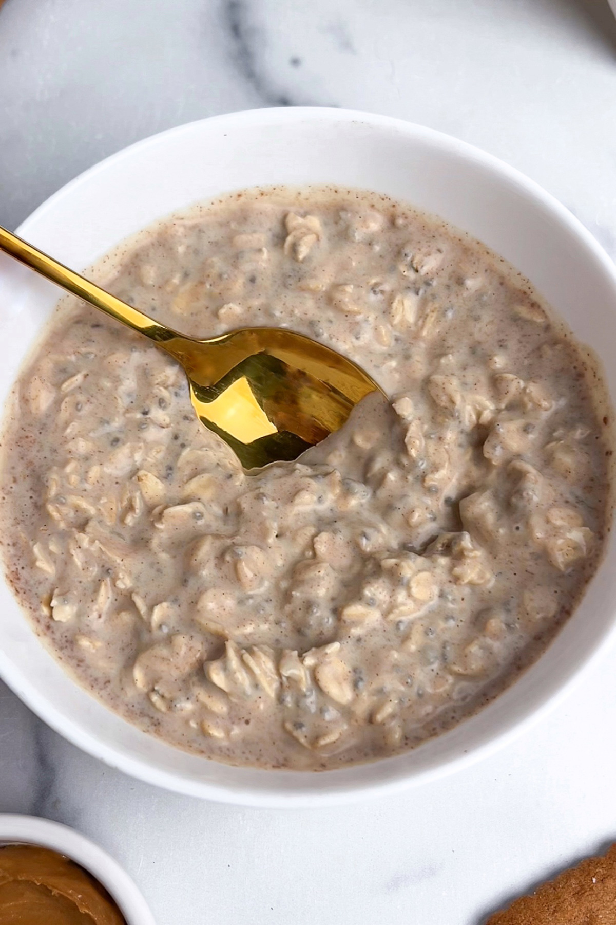 Biscoff overnight oats mixture being stirred together with a spoon until combined, ready to be covered and soaked overnight.