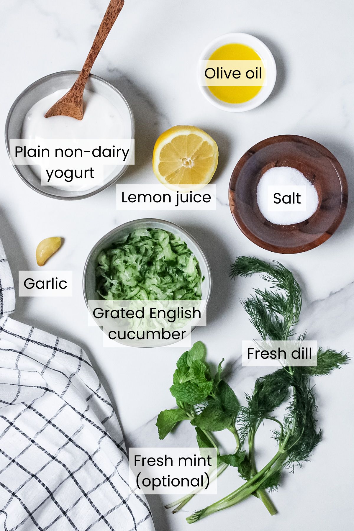Ingredients for dairy-free tzatziki: grated English cucumber, plain non-dairy yogurt, olive oil, lemon juice, fresh garlic, fresh dill, fresh mint (optional), and salt.
