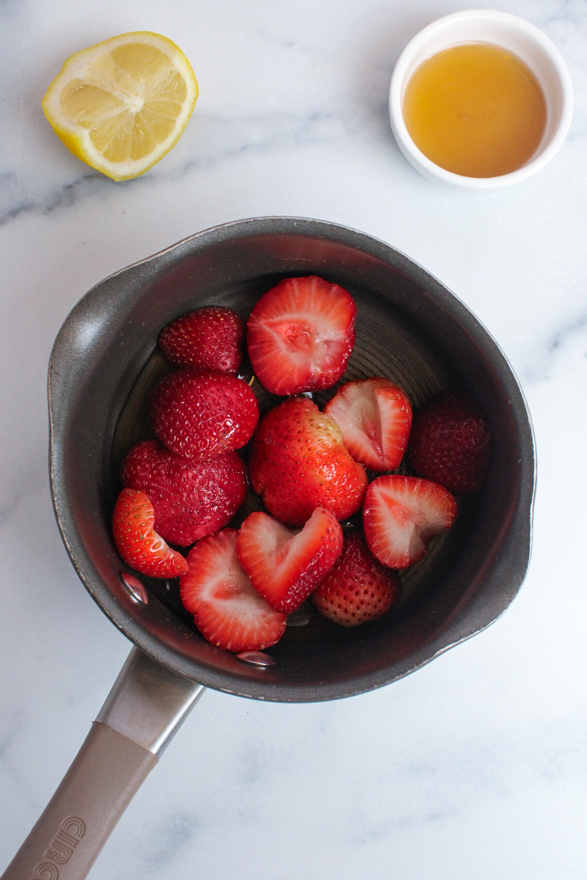 Chopped strawberries, maple syrup, and lemon juice combined in a saucepan for strawberry glaze.