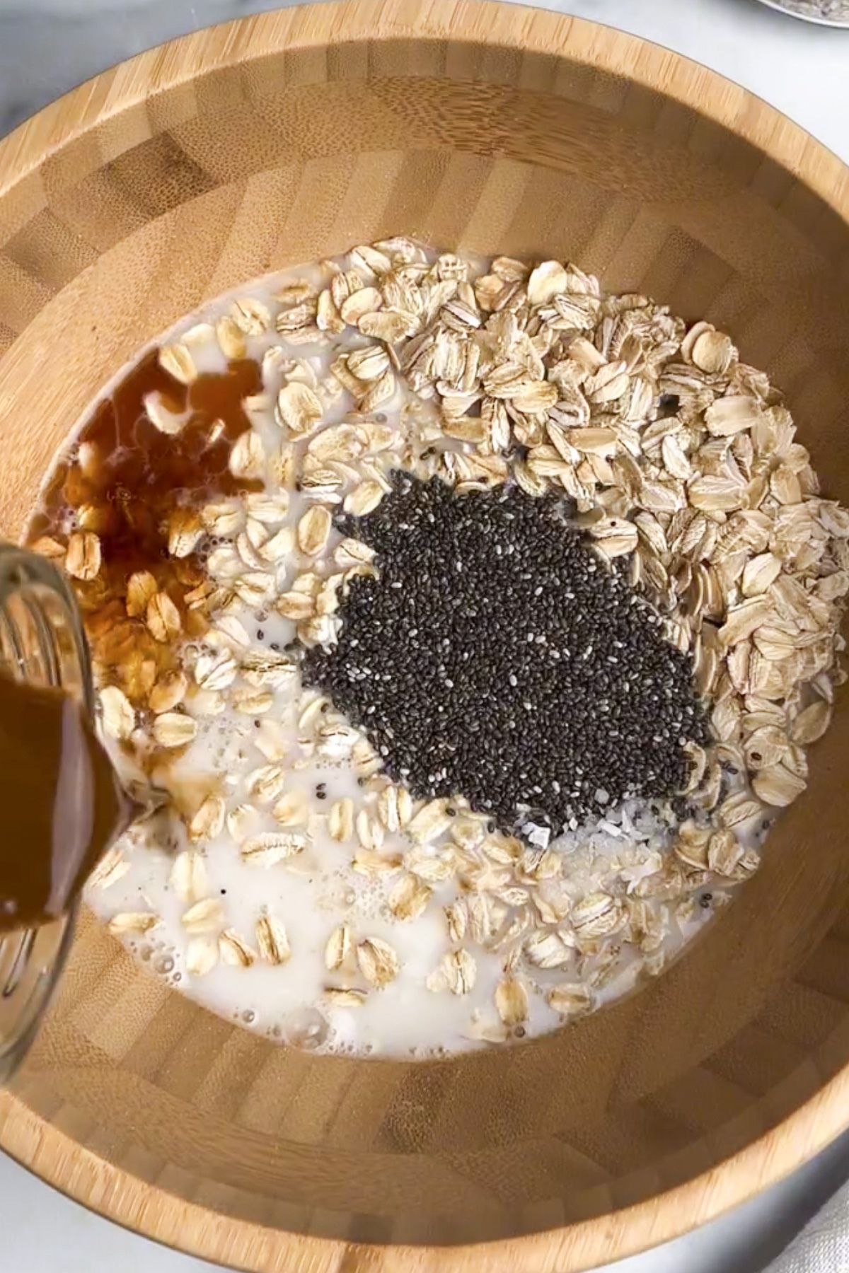 Oats, non-dairy milk, non-dairy yogurt, espresso, chia seeds, maple syrup, vanilla extract, and salt combined in a bowl.