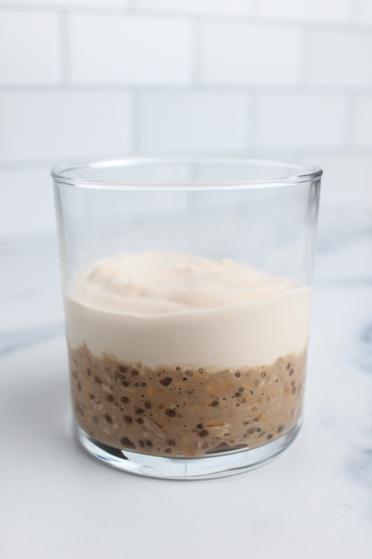 Layering thickened coffee overnight oats and non-dairy yogurt in a glass.